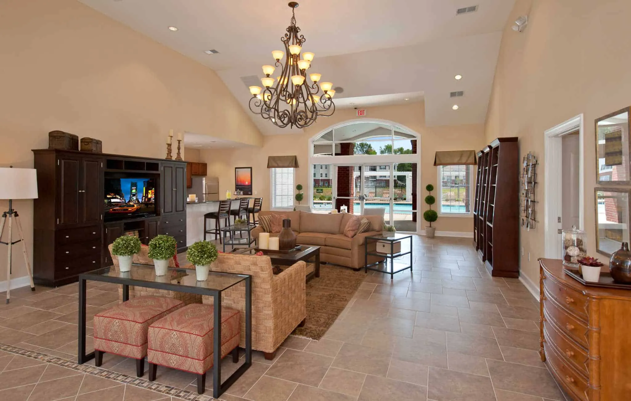 A spacious community clubhouse interior featuring high vaulted ceilings, a large ornate chandelier, a comfortable seating area